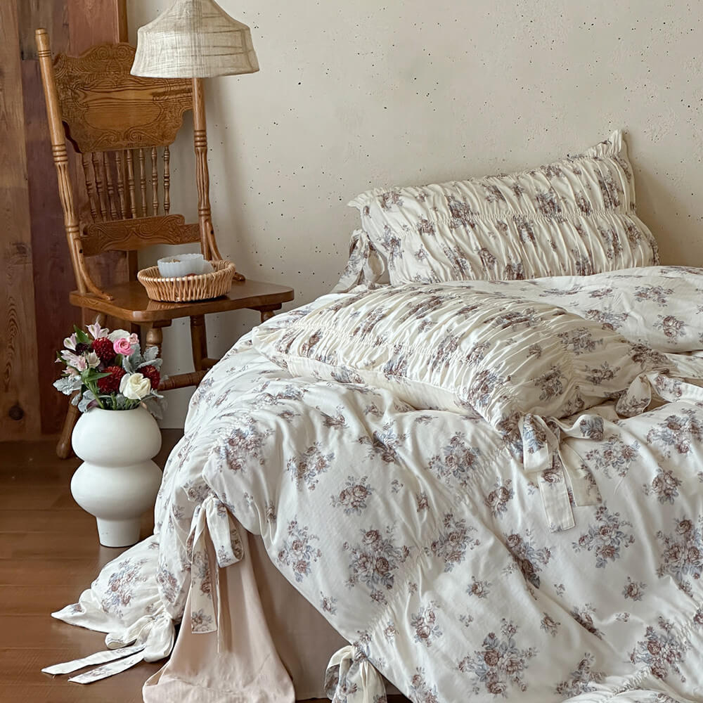 Faded rose cotton muslin bedding set with ruched pillow shams, ribbon-tie duvet details, and warm cottage bedroom styling.