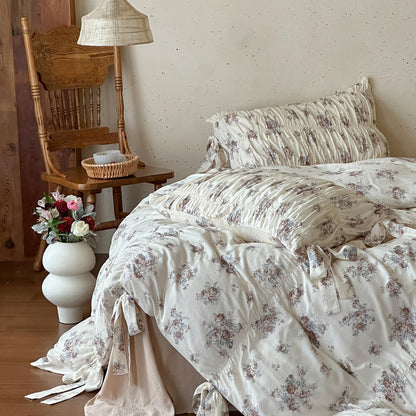 Faded rose cotton muslin bedding set with ruched pillow shams, ribbon-tie duvet details, and warm cottage bedroom styling.