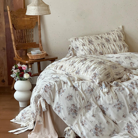 Faded rose cotton muslin bedding set with ruched pillow shams, ribbon-tie duvet details, and warm cottage bedroom styling.