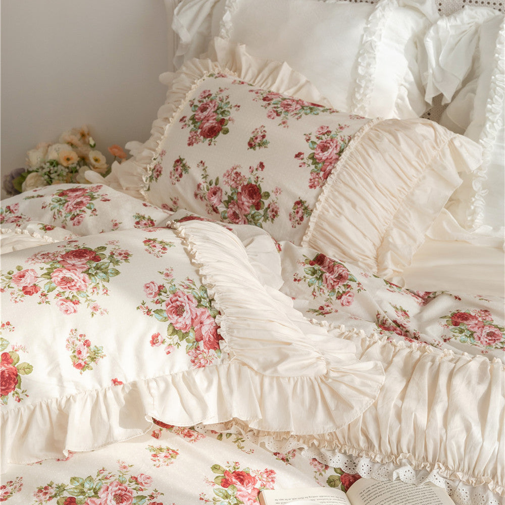 Floral cotton bedding set with ruffles, pink roses print, and matching pillows on a bed