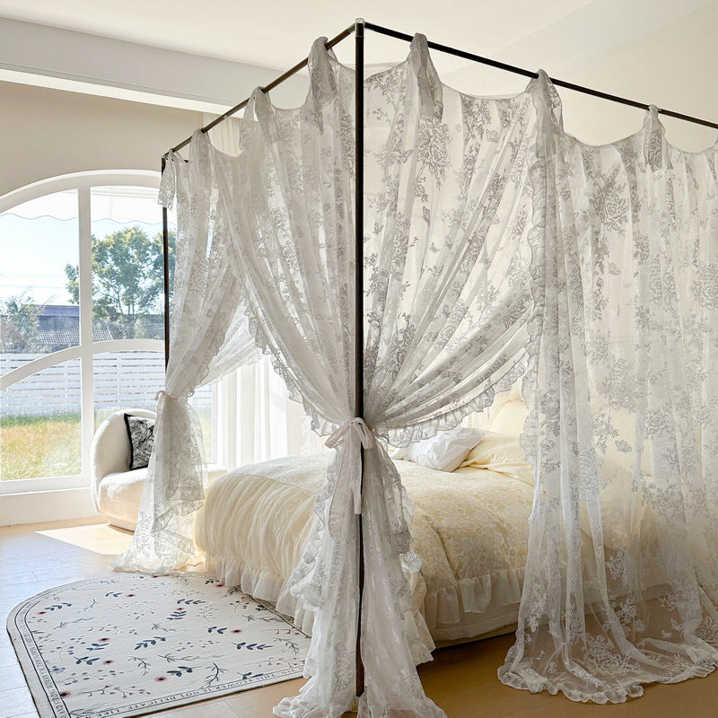 Floral lace canopy curtains on a four-poster bed with cozy bedding in a bright bedroom