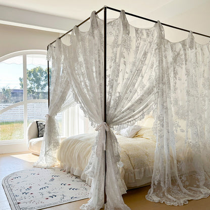 Floral lace canopy curtains on a four-poster bed with cozy bedding in a bright bedroom