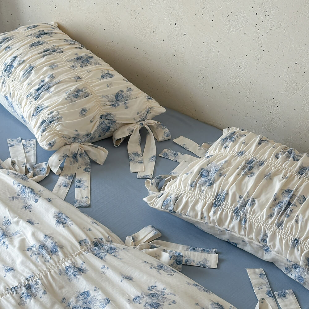 Close-up of blue floral cotton muslin bedding with ribbon tie pillow sham details