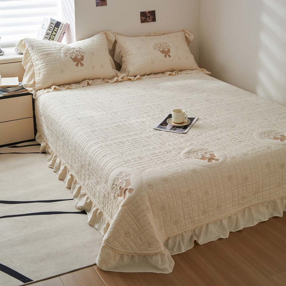 French embroidered style bedding set in cream, featuring soft quilted texture, central rose embroidery, and ruffled borders.