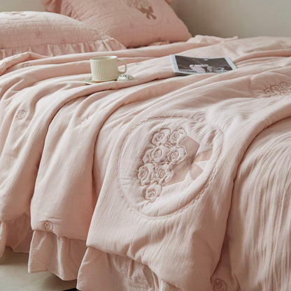 Close-up detail of the detailed rose embroidery and subtle diamond quilting on the pink French-style bedding set.