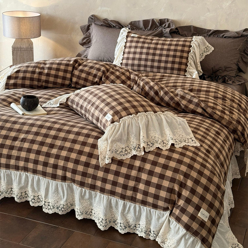 Plaid bedspread with lace details on a bed in a bedroom setting.