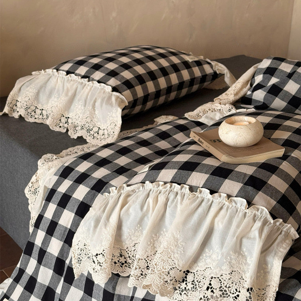 Black and white checkered bedspread with lace trim on a bed.