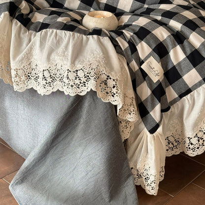 Black and white checkered blanket draped over a textured surface with lace trim.