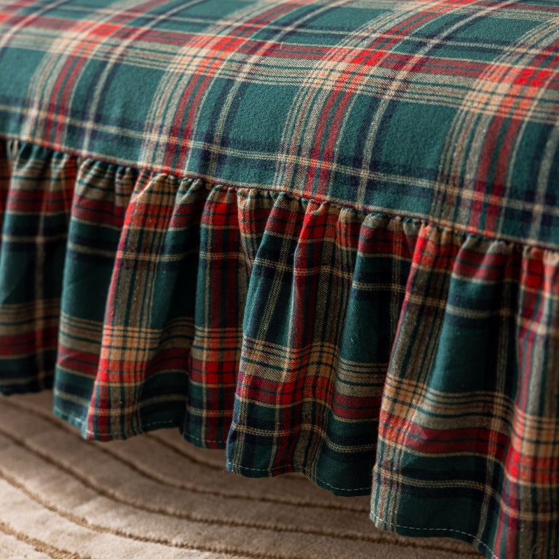 Green tartan plaid Christmas sofa cover with ruffles on a beige textured carpet