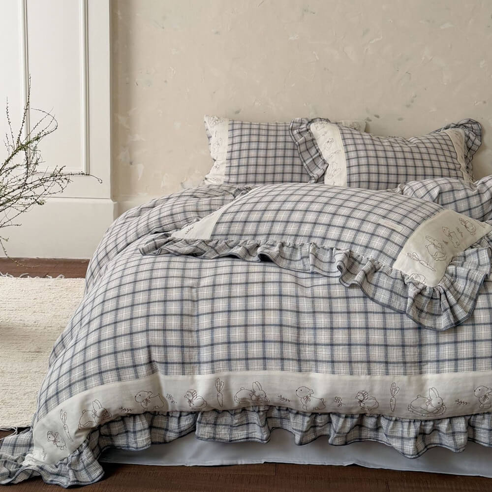 Grey plaid cotton muslin bedding set with ruffled trim on bed in cozy bedroom