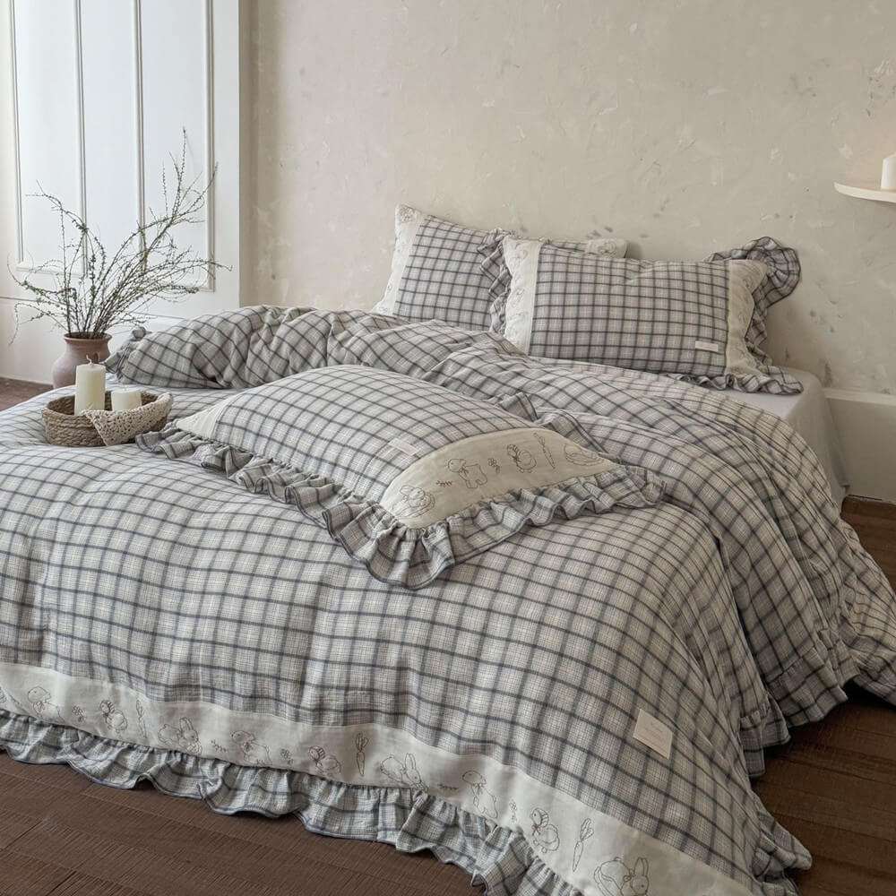 Grey plaid cotton muslin bedding set with ruffled trim on a bed in a cozy, natural bedroom.