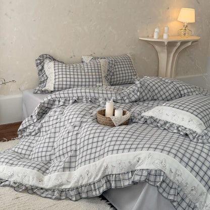 Grey plaid cotton muslin bedding set with ruffled trim on bed, cozy lamp and candles nearby