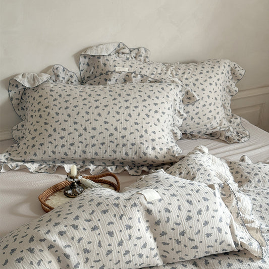 Grey floral cotton gauze bedding set with a pleated edge, styled on a neutral-toned bed.