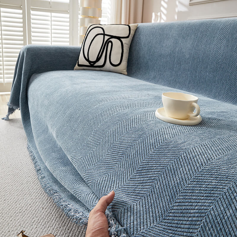 Blue herringbone chenille sofa cover with modern pillow and teacup in sunlit living room