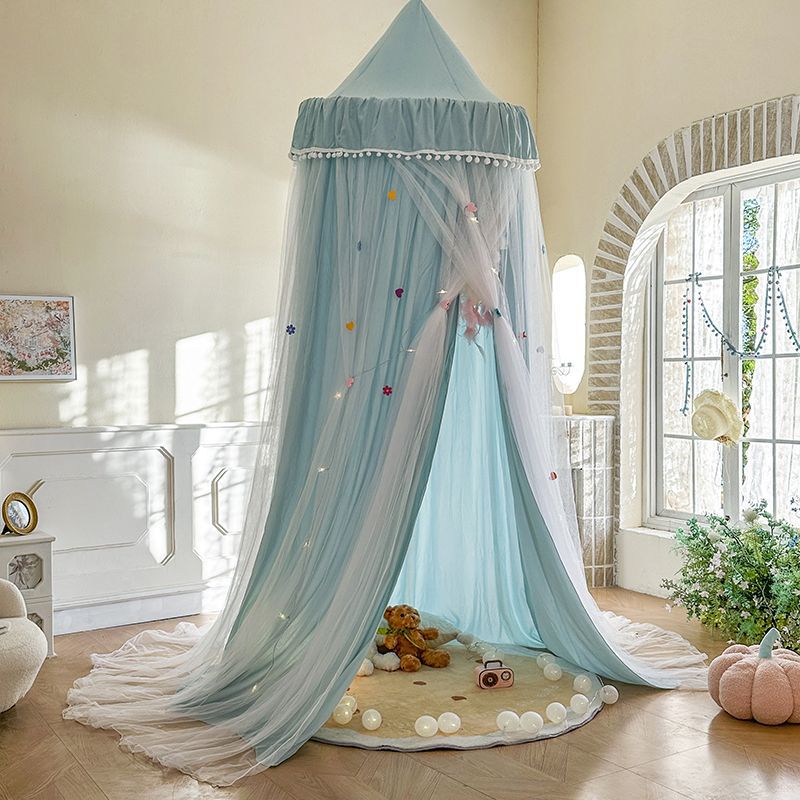 Blue kids bed canopy tent with sheer drapes and fairy lights in a cozy, sunlit room.
