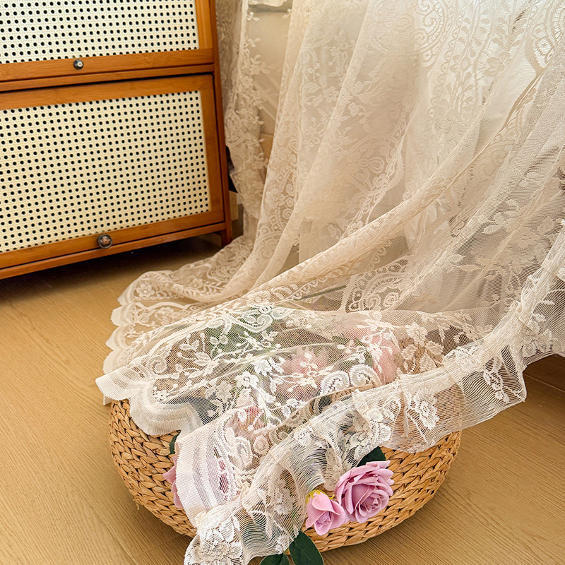 Elegant lace bed canopy curtain draped over basket with pink flowers on wooden floor