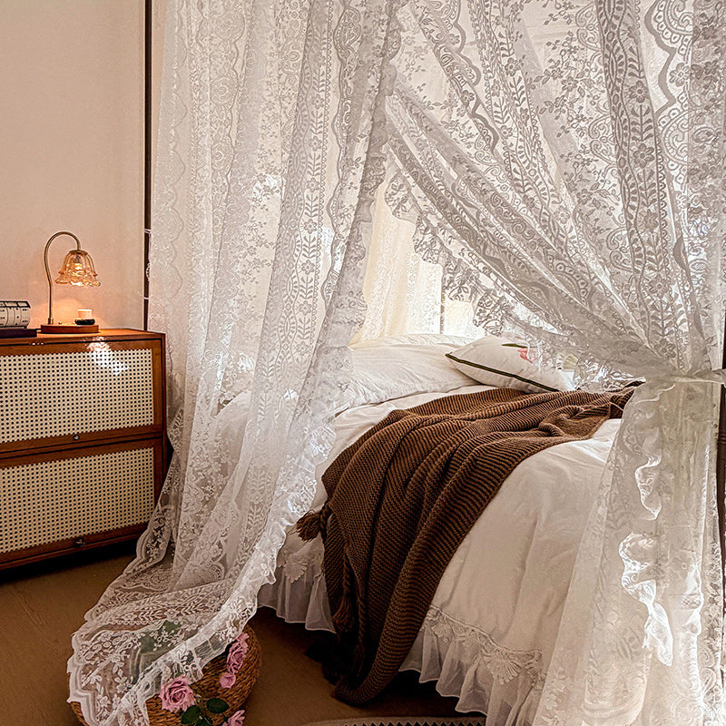 Romantic lace canopy curtains on four poster bed with cozy cotton bedding and brown throw blanket