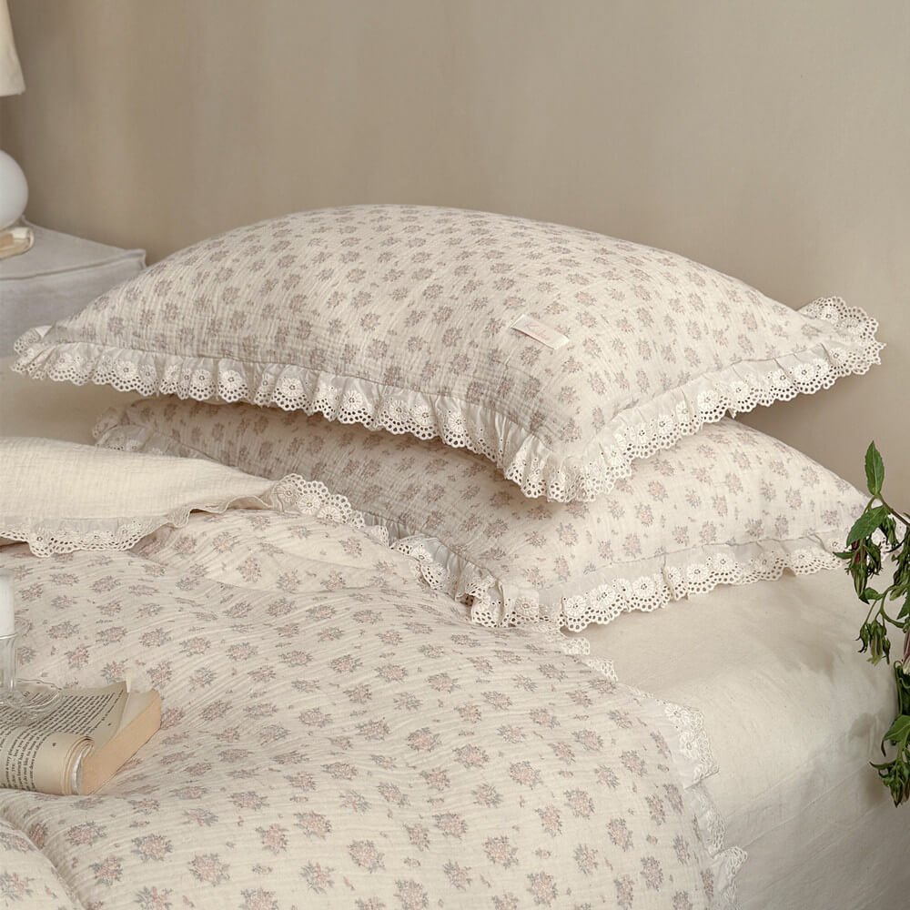 Two stacked vintage floral ruffle pillows with exquisite embroidered hollow-out lace trim, perfect for a cozy country style bedding look.