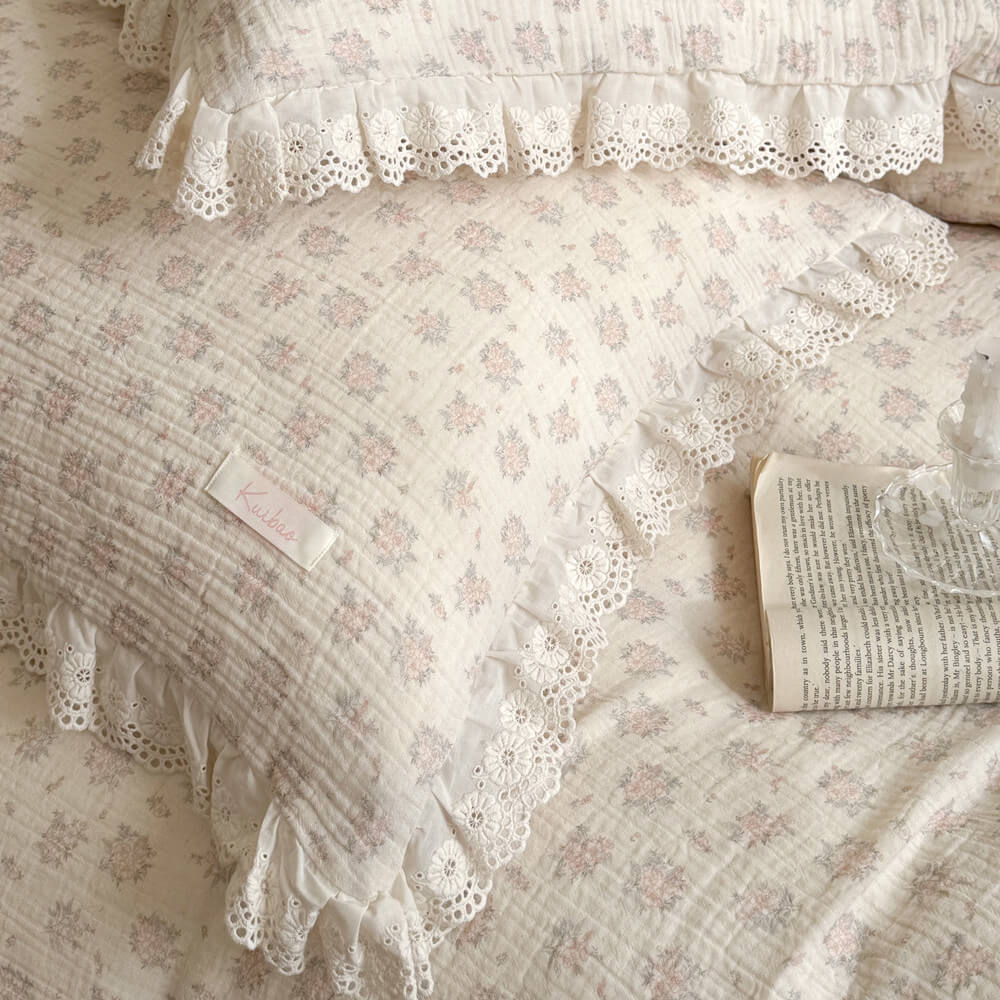 Detailed macro shot of a cottage style pink botanical print pillow with an open book, showcasing the delicate lace embroidery and woven fabric.