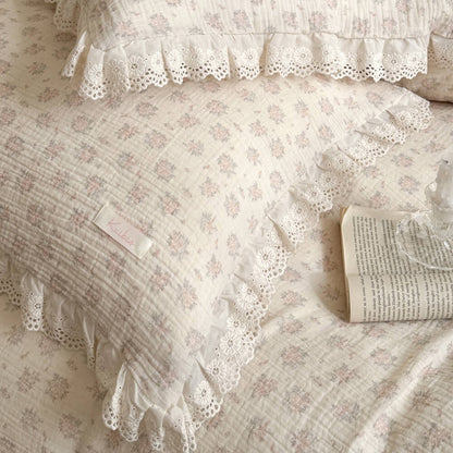 Detailed macro shot of a cottage style pink botanical print pillow with an open book, showcasing the delicate lace embroidery and woven fabric.