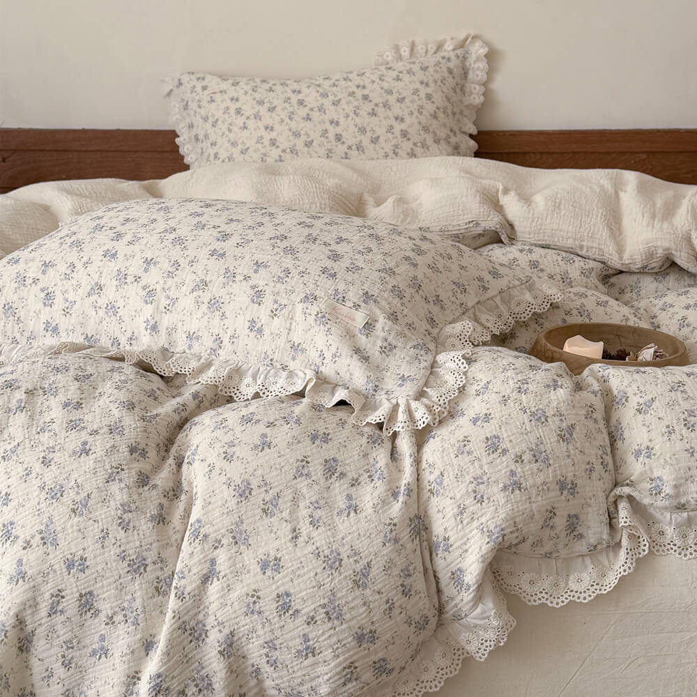 Close-up layered view of blue rose bedding set with ruffled pillowcases and floral duvet cover