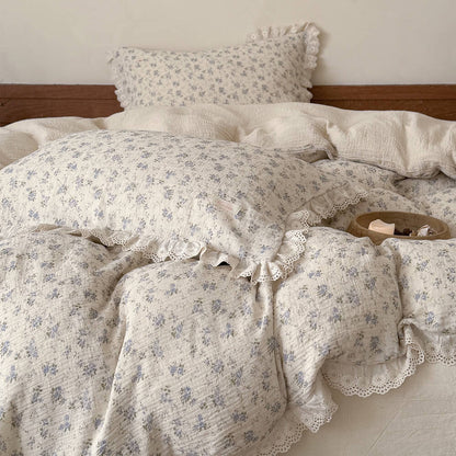 Close-up layered view of blue rose bedding set with ruffled pillowcases and floral duvet cover