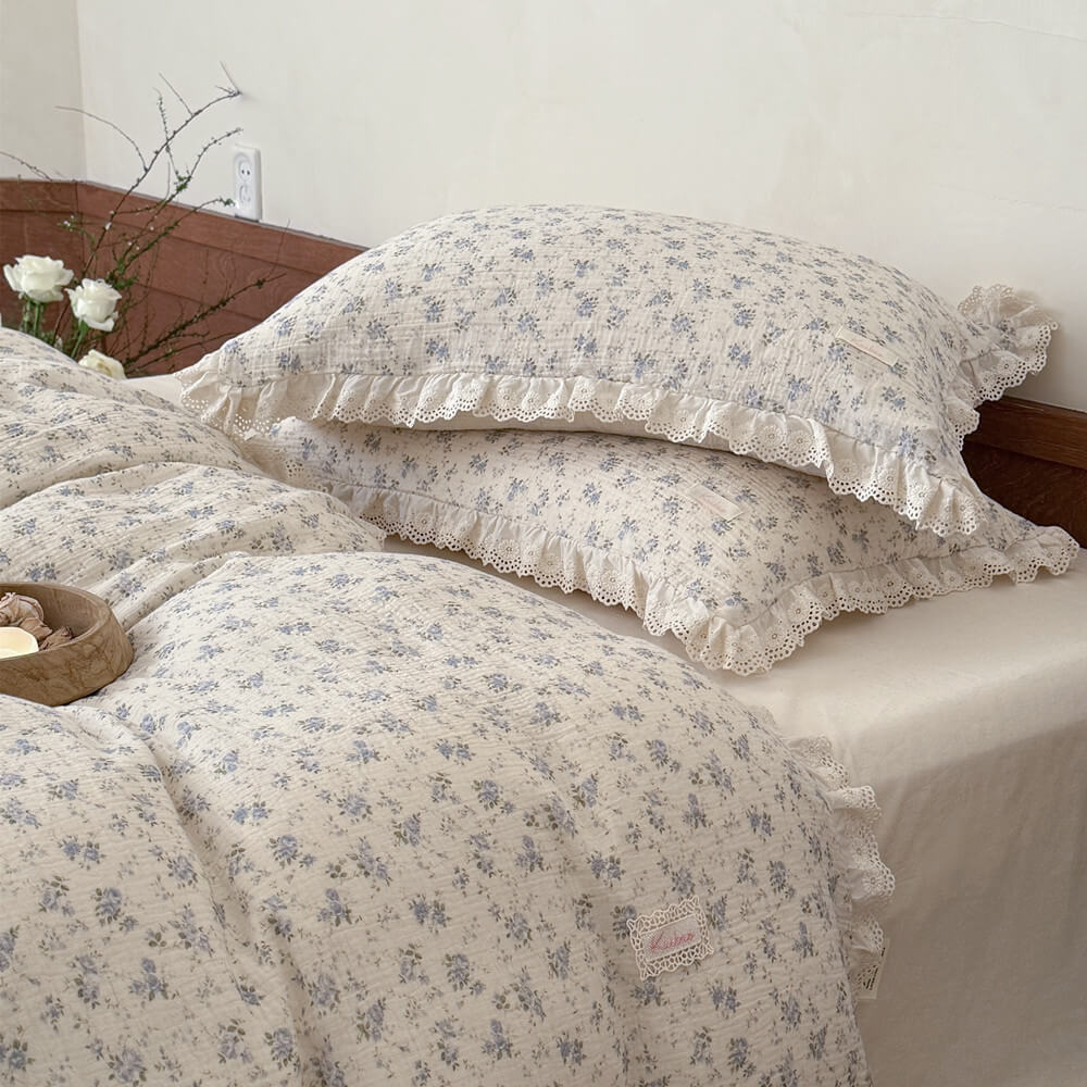 Ivory cotton linen bedding layered with matching blue rose floral pillowcases