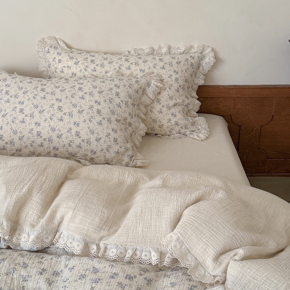 Detail view of blue rose cotton linen bedding with lace ruffle trim and floral pillowcase