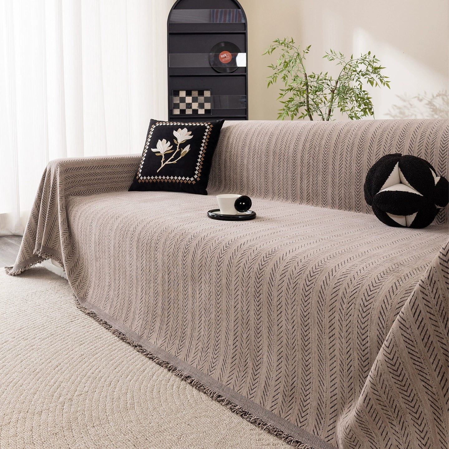 Modern herringbone one-piece sofa cover in a cozy living room with decorative pillows and plants.