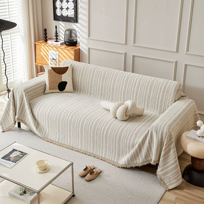 Modern beige herringbone one-piece sofa cover in a sunlit living room with neutral decor