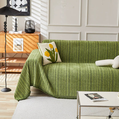 Modern living room with green herringbone one-piece sofa cover, floral pillow, and minimalist decor