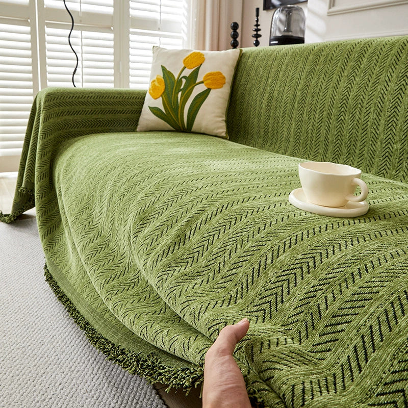 Green herringbone one-piece sofa cover with tasseled edge, on sofa with tulip pillow and cup