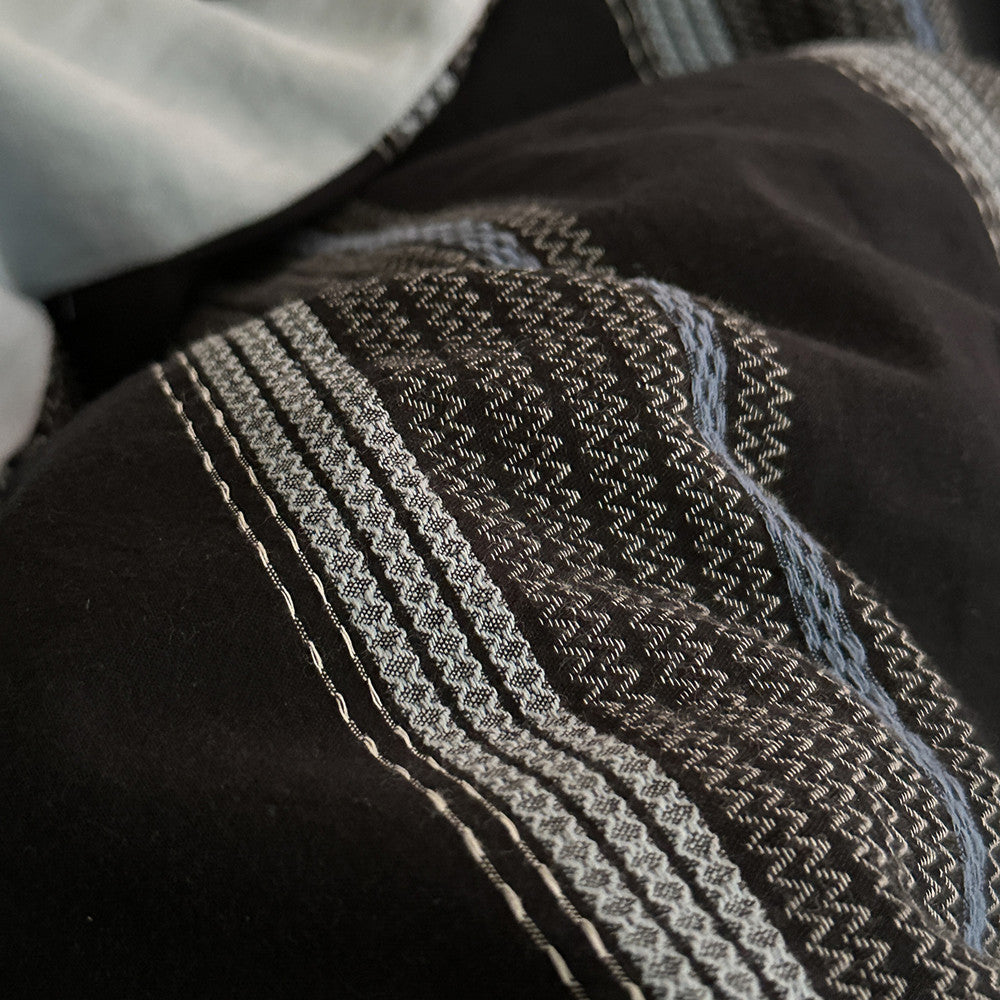 Close-up of black fabric with intricate jacquard cotton weaving in gray and blue patterns