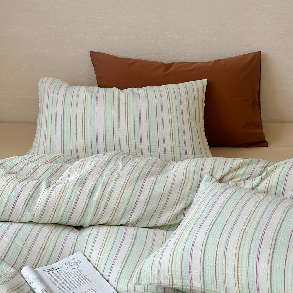 Modern striped duvet cover set with pillows on a bed, soft pastel cotton bedding