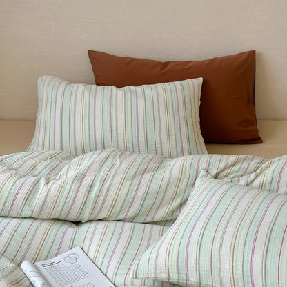 Modern striped duvet cover set with pillows on a bed, soft pastel cotton bedding