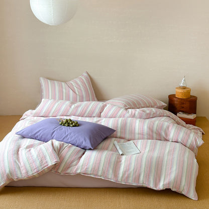 Modern striped duvet cover set with pink, green, and white cotton bedding in cozy bedroom