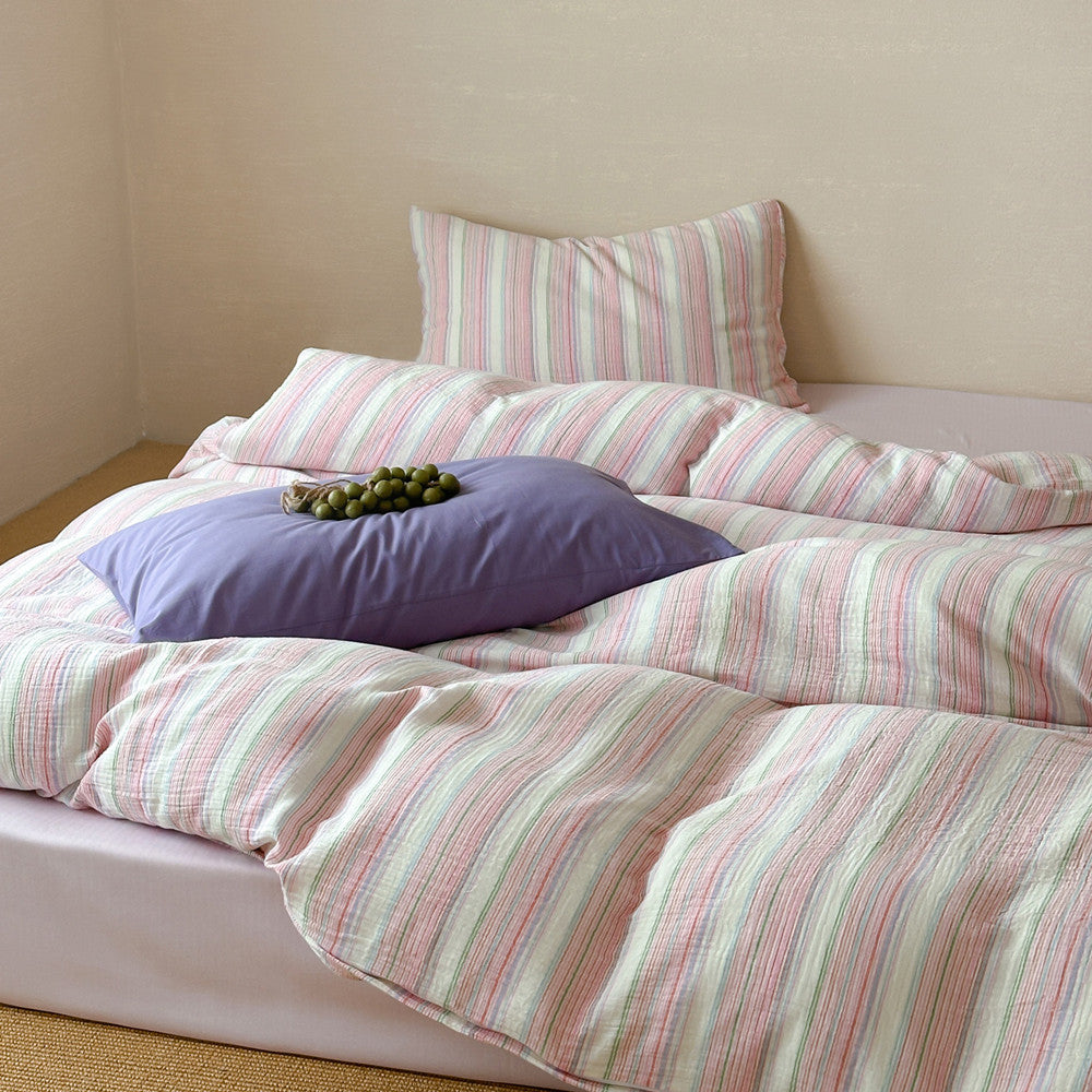 Modern striped cotton duvet cover set with pastel colors and matching pillowcases on a bed