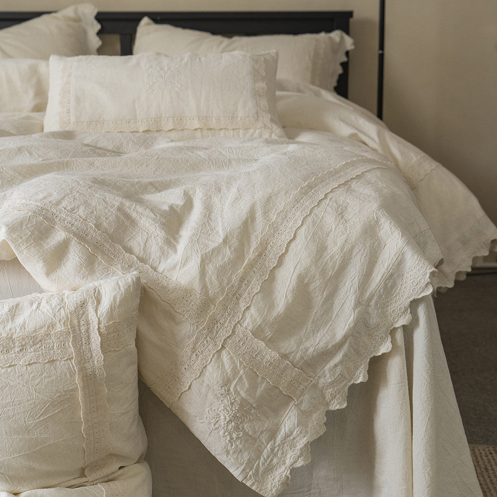 Styled shot of the Natural Linen Cotton Duvet Cover draped over a bed, showcasing the delicate eyelet lace border and embroidered detailing on the duvet and accent pillows, emphasizing the vintage texture.
