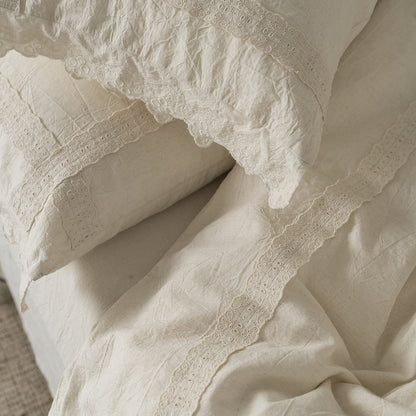 Close-up overhead view of the Natural Linen Cotton fabric and lace detailing on a pillow sham and the duvet cover, focusing on the wrinkled texture and the elegant crochet/eyelet trim.