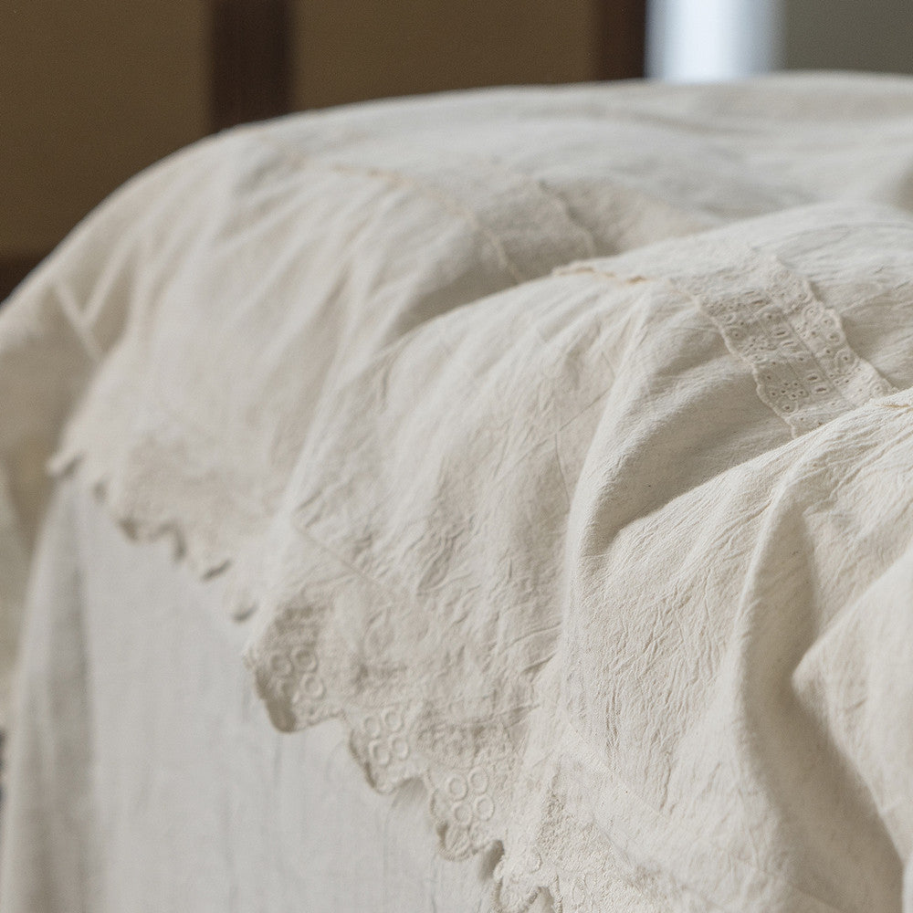 Detailed shot of the edge of the Linen Cotton Duvet Cover, highlighting the textured weave of the natural fabric and the scalloped, eyelet lace edge trim on the border.