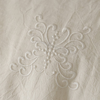 Macro close-up of the delicate white embroidered floral pattern featured on the Natural Linen Cotton Bedding Set, showcasing the stitch work detail.