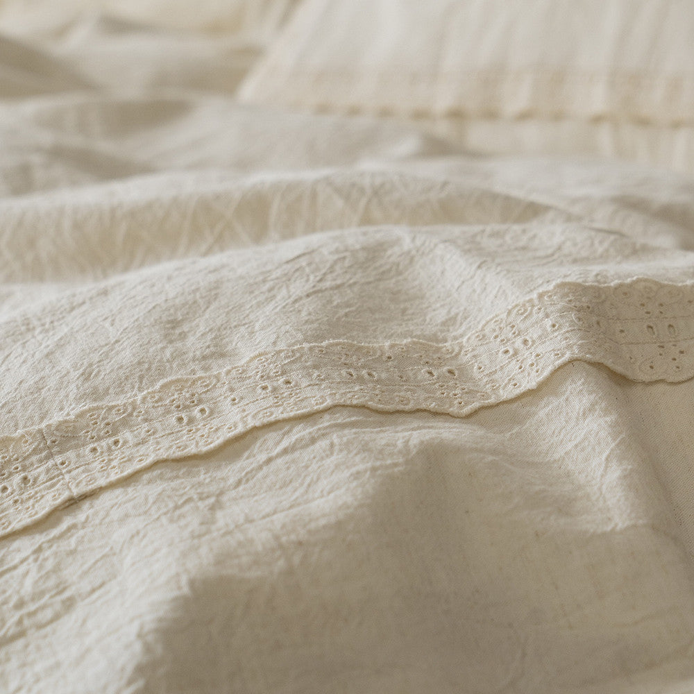 Extreme close-up on the detailed eyelet lace trim running along the edge of the Natural Linen Cotton Duvet Cover or sheet, highlighting the precision of the trim and the fabric weave.