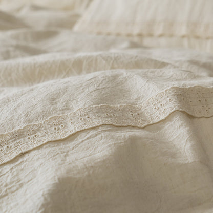Extreme close-up on the detailed eyelet lace trim running along the edge of the Natural Linen Cotton Duvet Cover or sheet, highlighting the precision of the trim and the fabric weave.