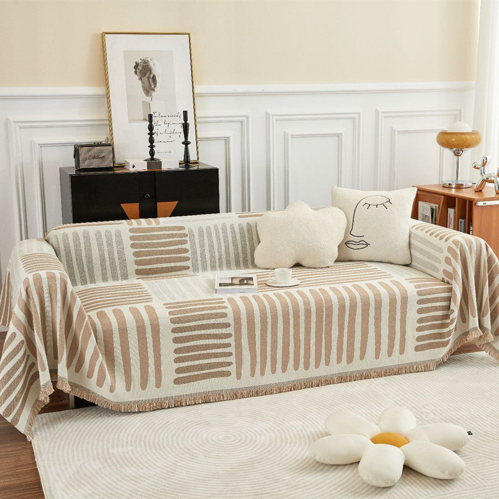 Reversible geometric sofa cover in beige and taupe on modern couch with accent pillows, StuffedHome