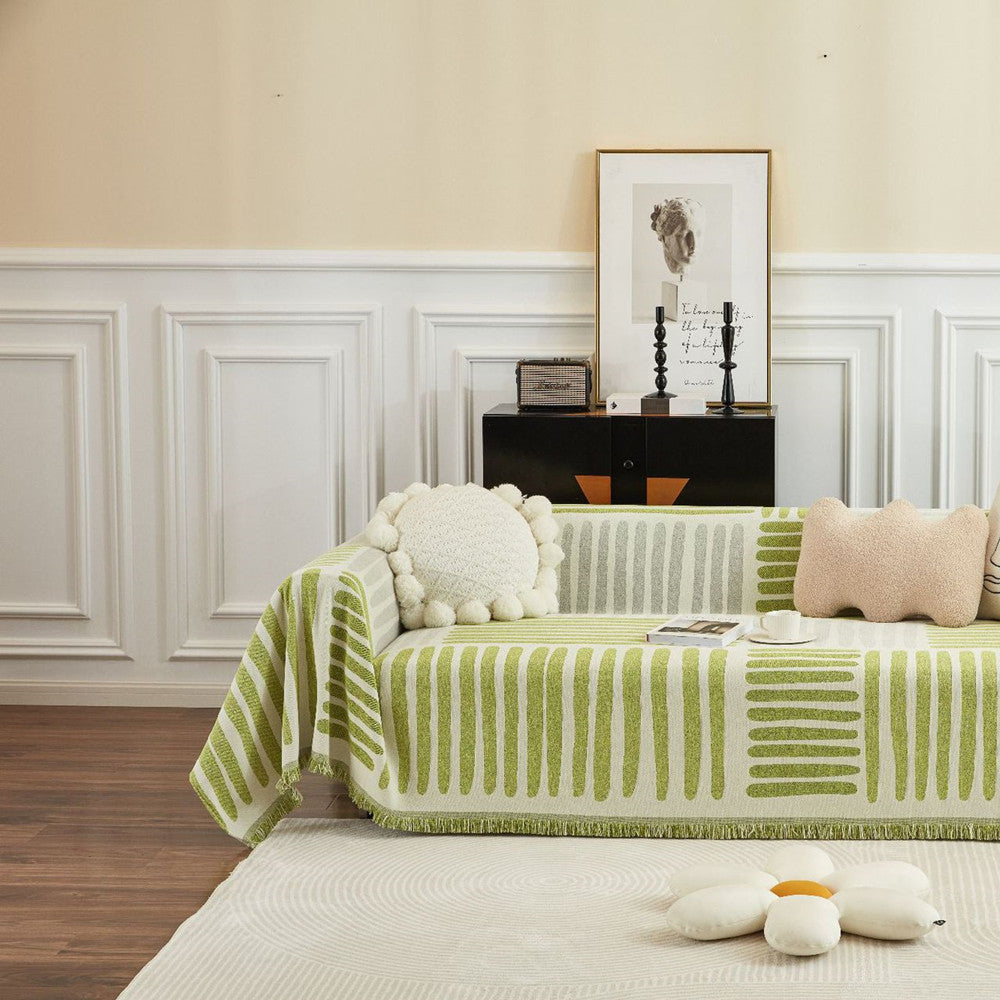 Green and white geometric reversible sofa cover on couch with plush pillows in modern living room