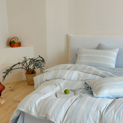 Side angle full view of the blue Pastel Cotton Striped Bedding Set styled neatly on a white bed frame.