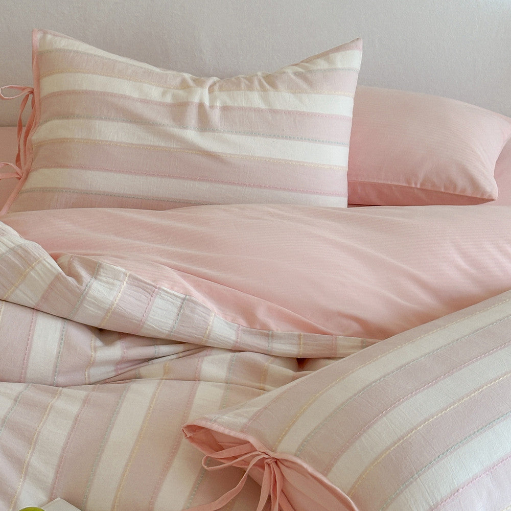 Full display of the pink Pastel Cotton Striped Bedding Set with matching solid color sheet and decorative bow-tie pillowcase.