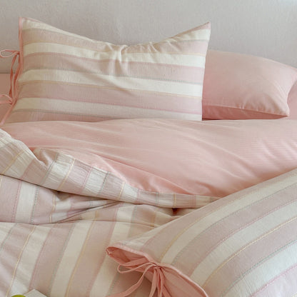 Full display of the pink Pastel Cotton Striped Bedding Set with matching solid color sheet and decorative bow-tie pillowcase.