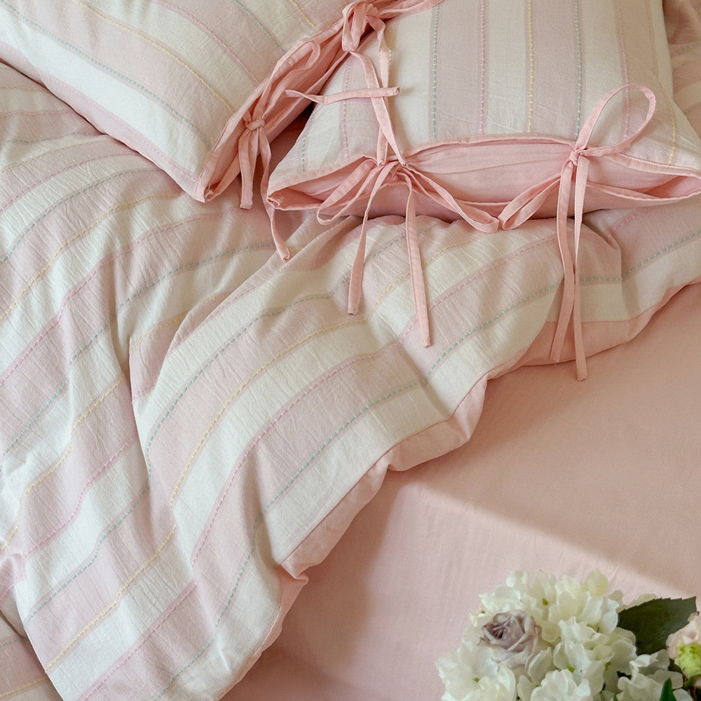 Close-up of pink Pastel Cotton Striped Bedding Set showcasing tie-detail pillowcases and cozy fabric texture.