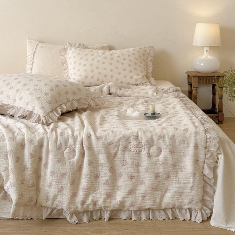 Full bed scene with pink floral cotton comforter, ivory ruffled trim, and bedside lamp